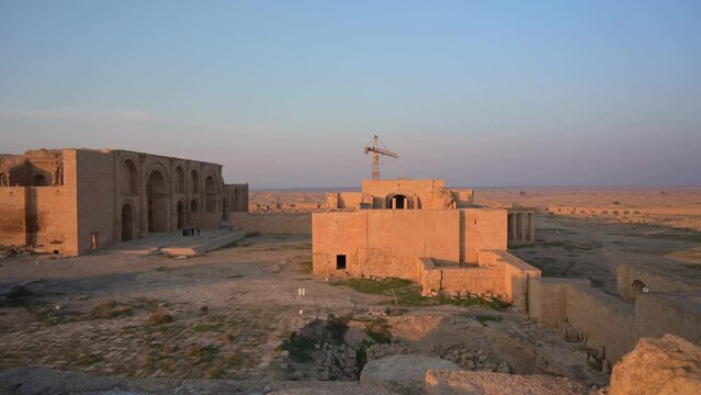 Hatra ruins in middle of desert with crane and sky in background at sunset, Iraq. FPV