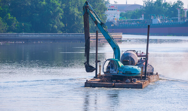 An excavator on a tugboat while sailing in the middle of river