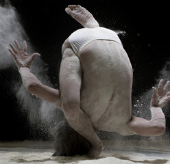 Obraz na płótnie Canvas Male gymnast exercising in white dust cloud shot