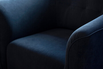 Upholstered furniture made of velor blue fabric with rounded elbows close-up. An element of upholstered furniture with a stitched sidewall in deep shadows with an empty space for text with copy space.
