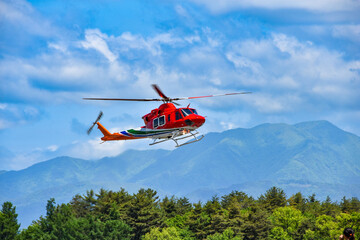 Fototapeta na wymiar 大自然の中を飛ぶ防災ヘリコプター