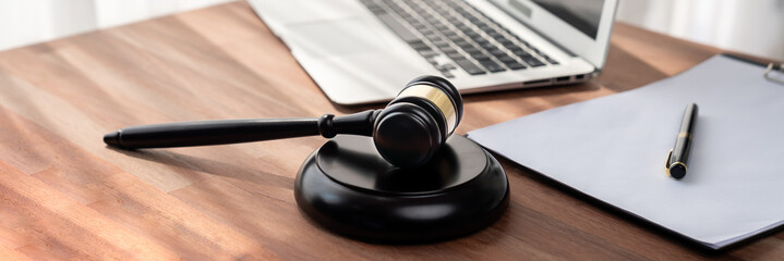 Closeup wooden gavel hammer with laptop and book and pen on desk on wooden office table background...