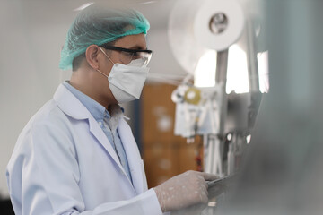Worker in personal protective equipment or PPE inspecting quality of mask and medical face mask...
