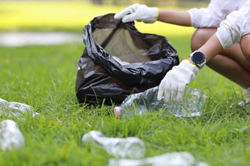 Young beautiful asian volunteer woman hands holding garbage bag and picking up litter while...