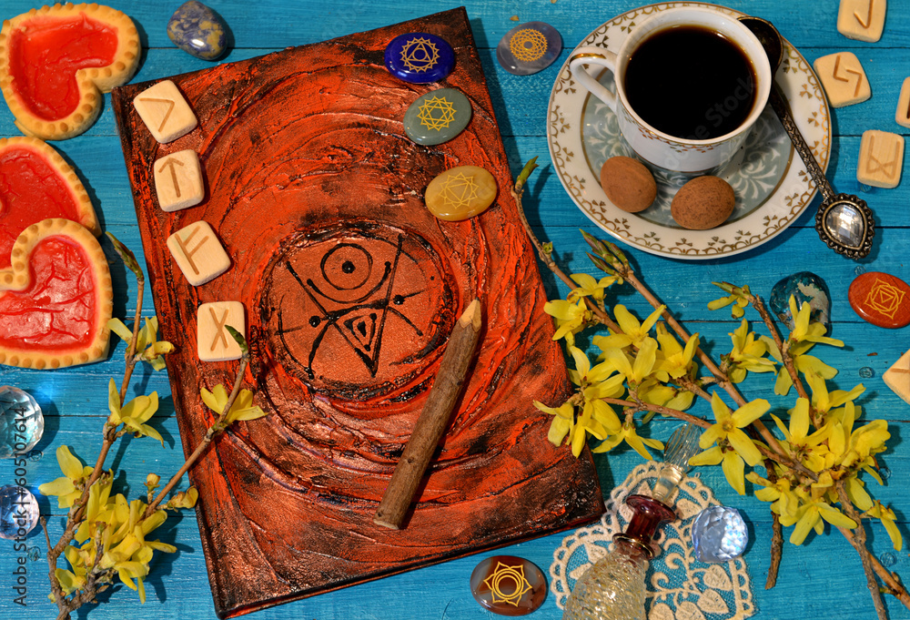 Wall mural Old magic book with spells, runes, crystals and cup on witch altar table. Occult, esoteric and divination still life.