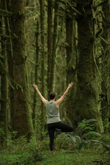 Woman performing meditation and yoga in a lush forest