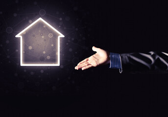 Conceptual image with hand pointing at house or main page icon on dark background - 605109835
