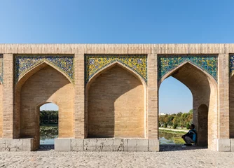 Lichtdoorlatende gordijnen Khaju Brug Man sitting under arch on historic Khaju Bridge (Pol-e Khajoo) on Zayanderud River in Isfahan, Iran. Heritage and tourist attraction.