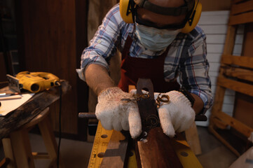 Carpenter working hard while planing on wood with a manual wood planer or plane tool in workshop or carpentry workplace, Craftsman, Handyman concept. Selective focus on the hand of carpenter.