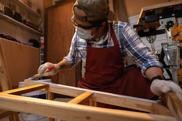 Craftsman, Carpenter using a paintbrush painting to wooden bar chair handmade at woodworking workshop or carpentry workplace.