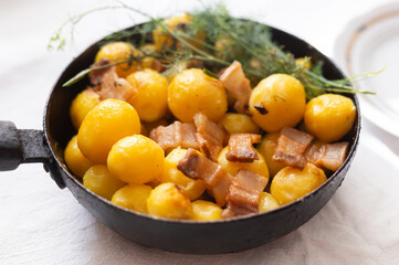 traditional homemade dish. fried young potatoes with bacon and dill serving in skillet