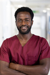 Obraz premium Unaltered portrait of african american male doctor in scrubs smiling, standing in hospital corridor