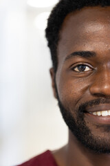 Obraz premium Unaltered portrait of half face of happy african american male doctor smiling, with copy space