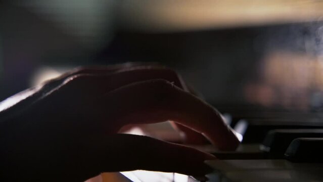 Close-up hands of unrecognizable musician male pianist playing classics music on piano in concert hall. Close up side view of man music composer practicing piano. Shooting in slow motion