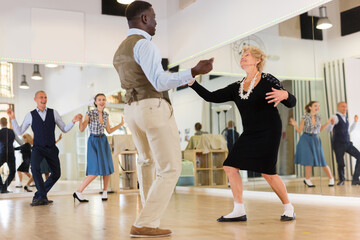 Lady learning to dance lindy hop with man in dance school