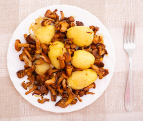 traditional dishes of Eastern European cuisine. Fried chanterelles with young potatoes on white plate. top view