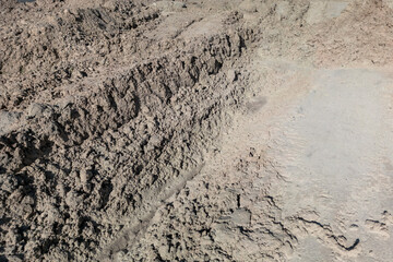 Open sand pit, for sand extraction during construction. The texture of sand and traces of the tread of large cars. Sand for construction work. Storage of sand at the construction site.