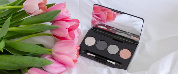 Obraz na płótnie Canvas Pink tulips, eye shadow palette with mirror on white background, women makeup cosmetics set