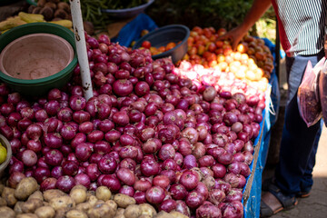 Different vegetables sold at market on Goa in India. Red onions, tomatoes and potatoes laid out in trays for sale. 