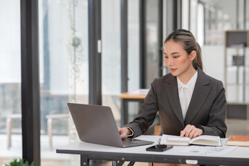 Fototapeta premium Young Asian businesswoman working on documents at office