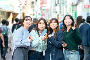 街中でスマホを使う若い女性達
