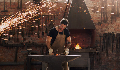 Hammer, anvil and fire with a man working in a plant for metal work manufacturing or production....