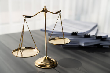 Shiny golden balanced scale and pile of legal paper on desk in lawyer office as concept justice and...