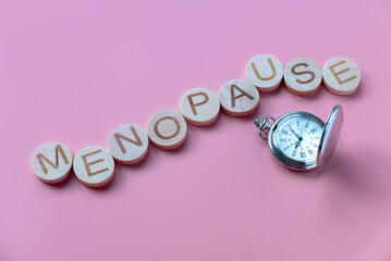 Alphabet form a word menopause over a watch. Healthcare and medical concept for women. Pink background. - obrazy, fototapety, plakaty