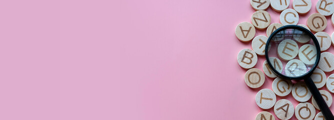 Concept of learning english, searching for word, and information. English alphabet letter and magnifying glass. Pink background with copy space.
