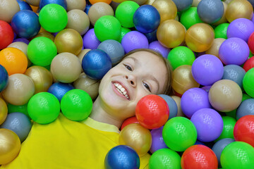 A little girl is having fun playing with colorful plastic balls on the playground