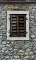 old window with shutters against stone wall on house