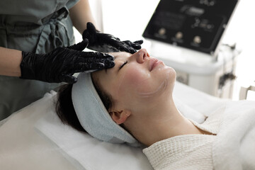 Relax woman indulges in a facial treatment at a beauty salon. A cosmetologist applies a...