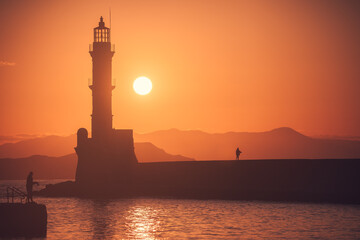 Greece's mesmerizing Chania: A breathtaking sunset and golden hour at the lighthouse in Crete; vibrant hues engulf the sky, illuminating the coastal beauty in a magical Greek setting