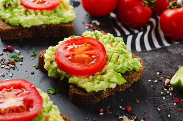 Avocado Toasts with Tomato, Healthy Snack or Breakfast on Dark Background