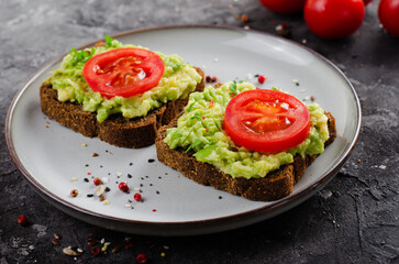 Avocado Toasts with Tomato, Healthy Snack or Breakfast on Dark Background
