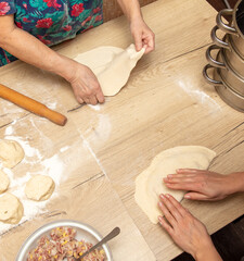 Obraz na płótnie Canvas Hands of women kneading dough for dumplings