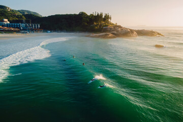 Sunrise on ocean with surfers on wave. Joaquina beach in Brazil