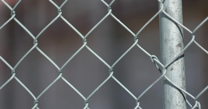 The camera's focus shifts between cinderblock walls of an empty building, and a chainlink fence with the camera totally defocused.