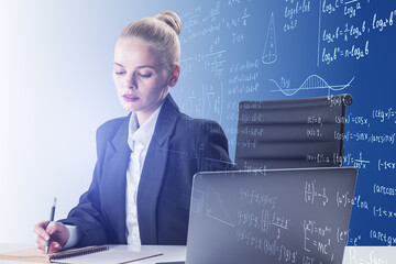 Portrait of attractive young blonde businesswoman at desk with laptop and mathematical formulas on...