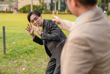 A nervous nerdy asian man cowers in fear after being confronted and accused by someone in public.