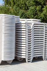 Stack of sun loungers on the beach. Preparing the beach for the new opening season. Lots of sun loungers stacked on top of each other next to the pool of water. 