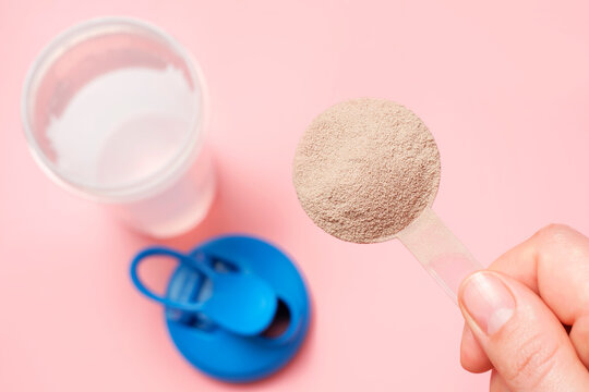 Making chocolate protein shake on pink background, top view.