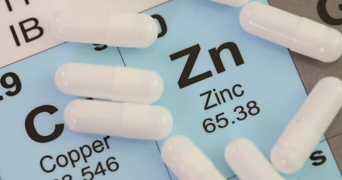 hemical element Zinc Zn with white tablets closeup. Zinc benefits for body symptoms of zinc deficiency
