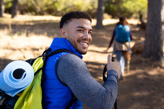 Portrait of happy biracial man looking at camera and smiling in forest, unaltered