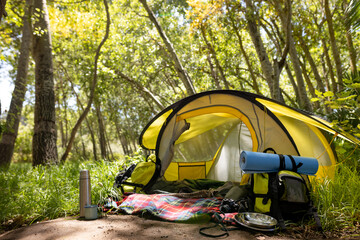 General view of tent with backpack and hiking equipment in forest, unaltered
