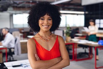 Portrait of happy african american businesswoman crossing arms and smiling at office, unaltered