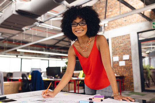 Happy african american businesswoman drawing architectural plans and smiling at office, unaltered