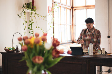 asian person reads recipe from ipad making cookies at home kitchen