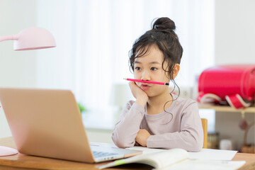 自宅でパソコンを見ながら勉強する女の子