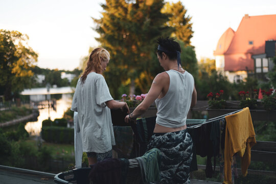 queer couple hang clothes washing together on balcony by lake